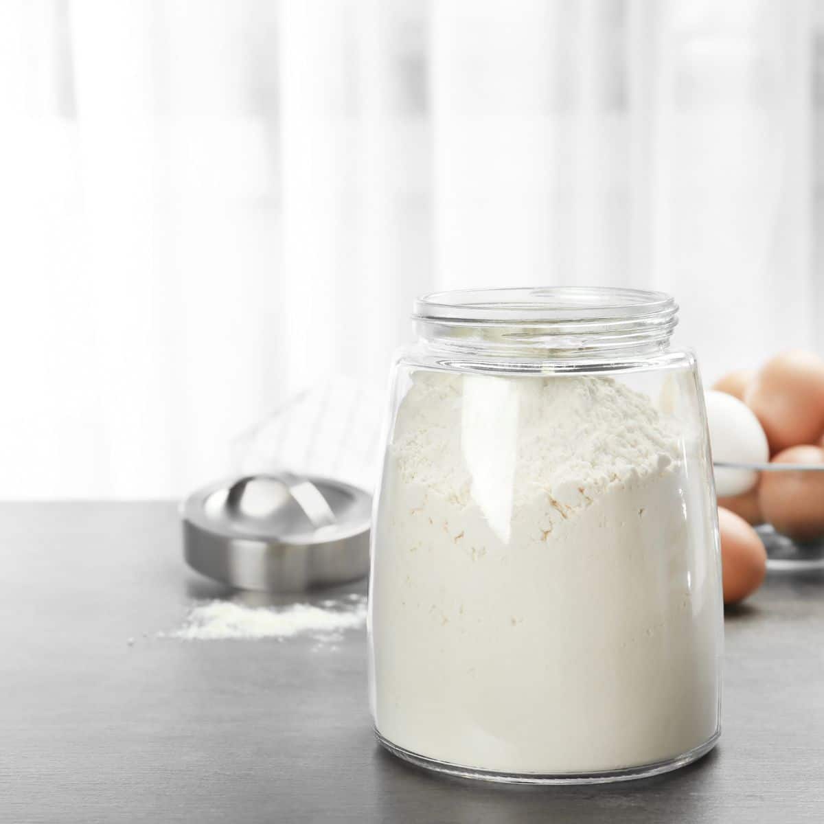 A mason jar filled with gluten free flour sitting on the counter.