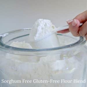 Scooping gluten-free sorghum-free flour out of a large jar.