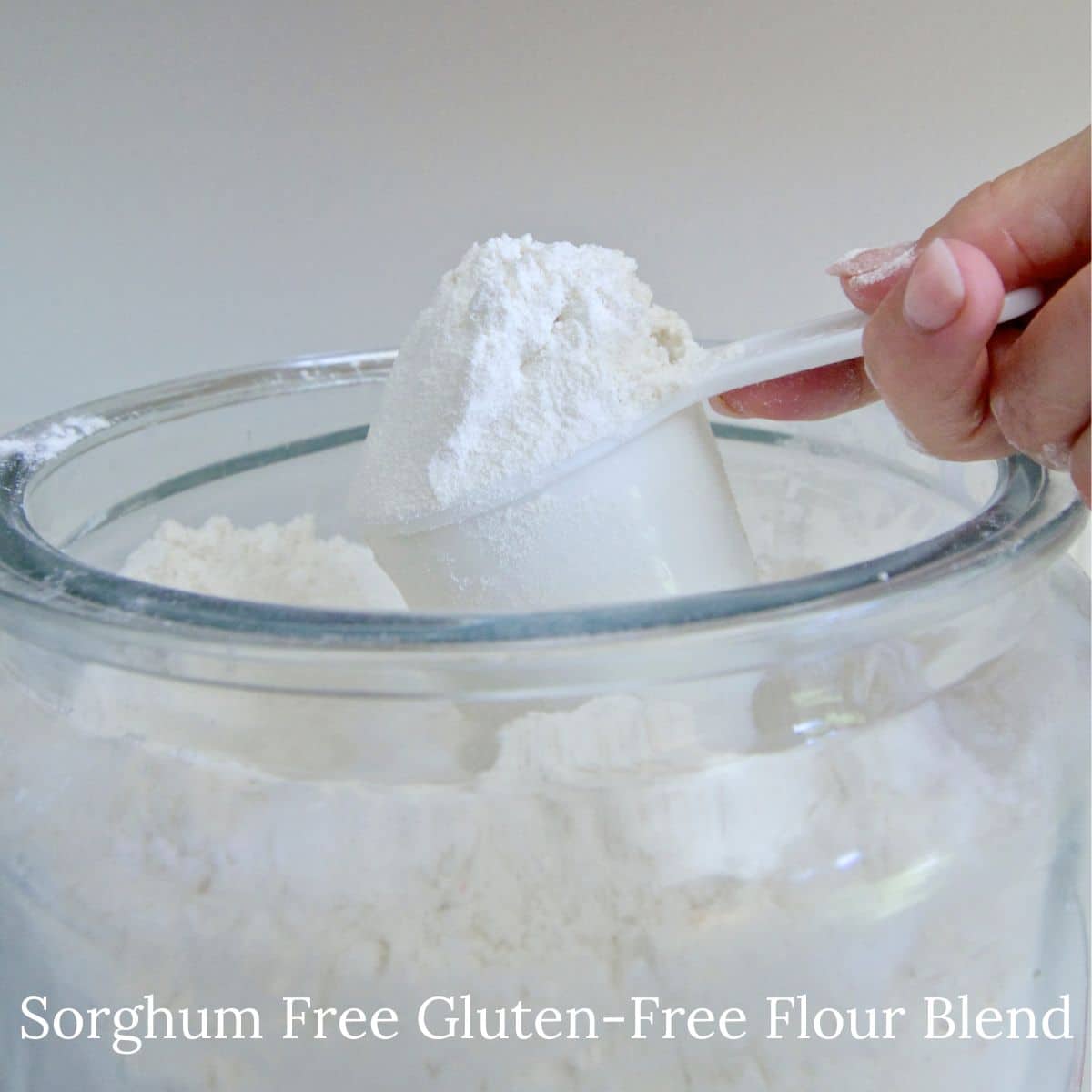 Scooping gluten-free sorghum-free flour out of a large jar.