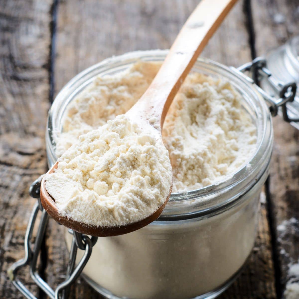 A jar filled with gluten free sorghum free flour. A wooden spoon is on top of the jar.