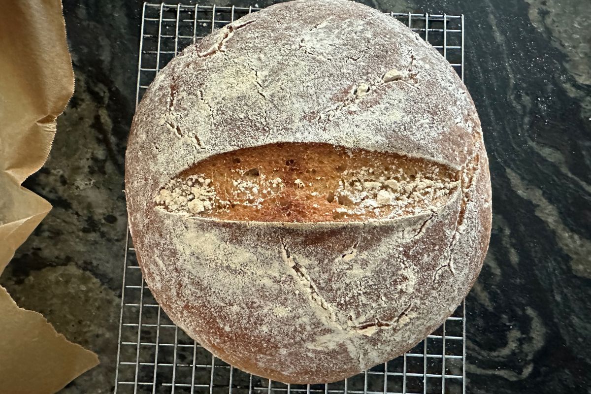 A baked gluten free sourdough boule on a wire cooling rack.