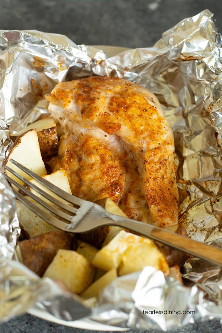 A seasoned chicken breast and potatoes cooked in an air fryer foil packet.