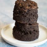 A stack of two gluten free chocolate biscuits on a small white plate.