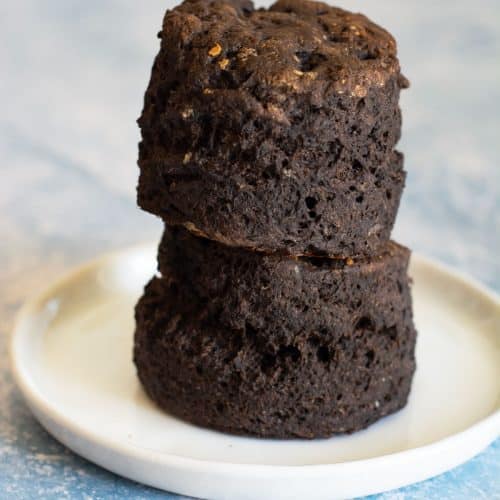 A stack of two gluten free chocolate biscuits on a small white plate.