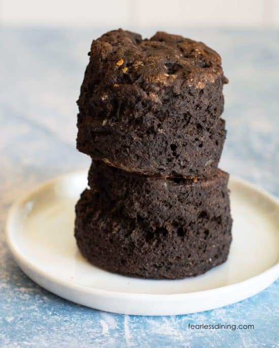 A stack of two gluten free chocolate biscuits on a small white plate.