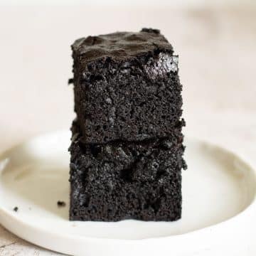 A stack of two fudgy brownies on a small white plate.