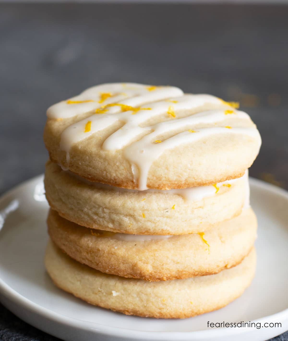 A stack of four lemon shortbread cookies on a white plate.