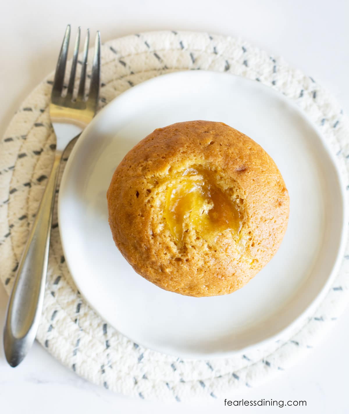 The top view of a marmalade muffin on a small white plate.