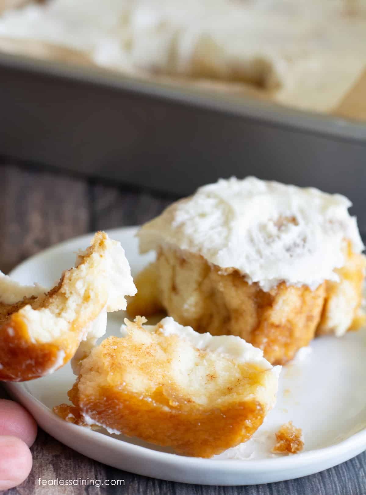 Pulling apart a cinnamon roll so readers can see the spirals of cinnamon sugar.