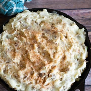 A shepherd's pie topped with mashed potatoes in a cast iron skillet.