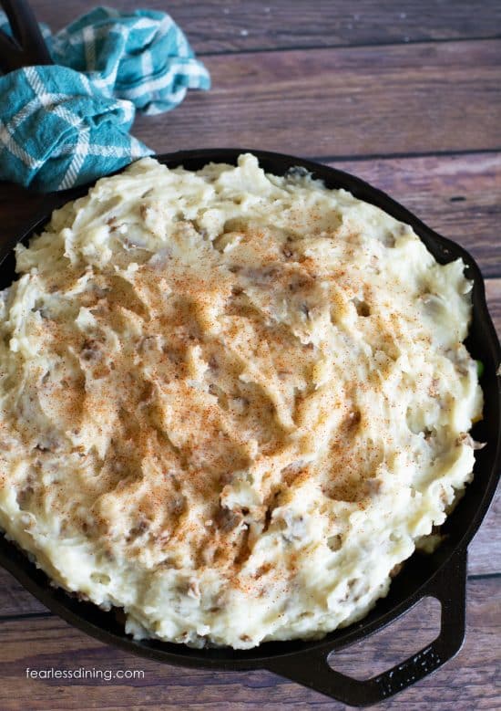 A shepherd's pie topped with mashed potatoes in a cast iron skillet.