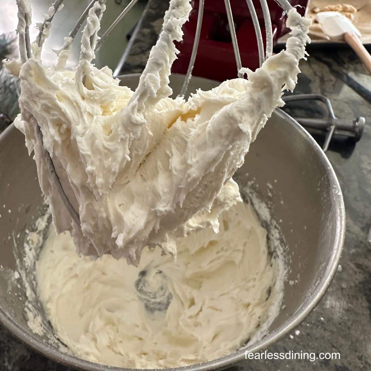 Frosting in a stand mixer and on the whisk attachment.