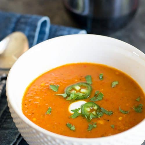 A white soup bowl filled with red shishito pepper soup.