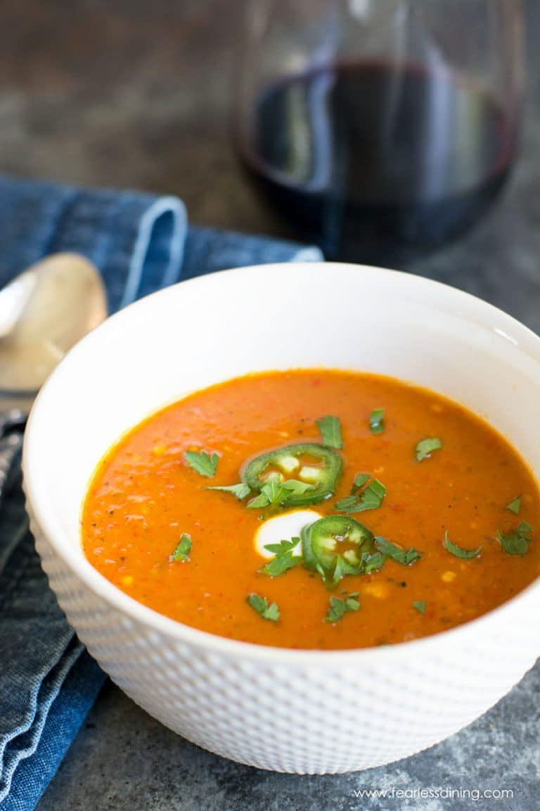 A white soup bowl filled with red shishito pepper soup.
