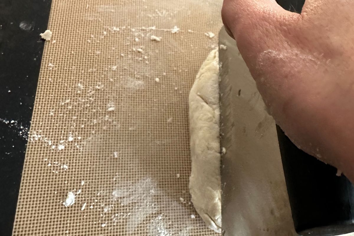 Using a scraper to cut the biscuit dough into squares.