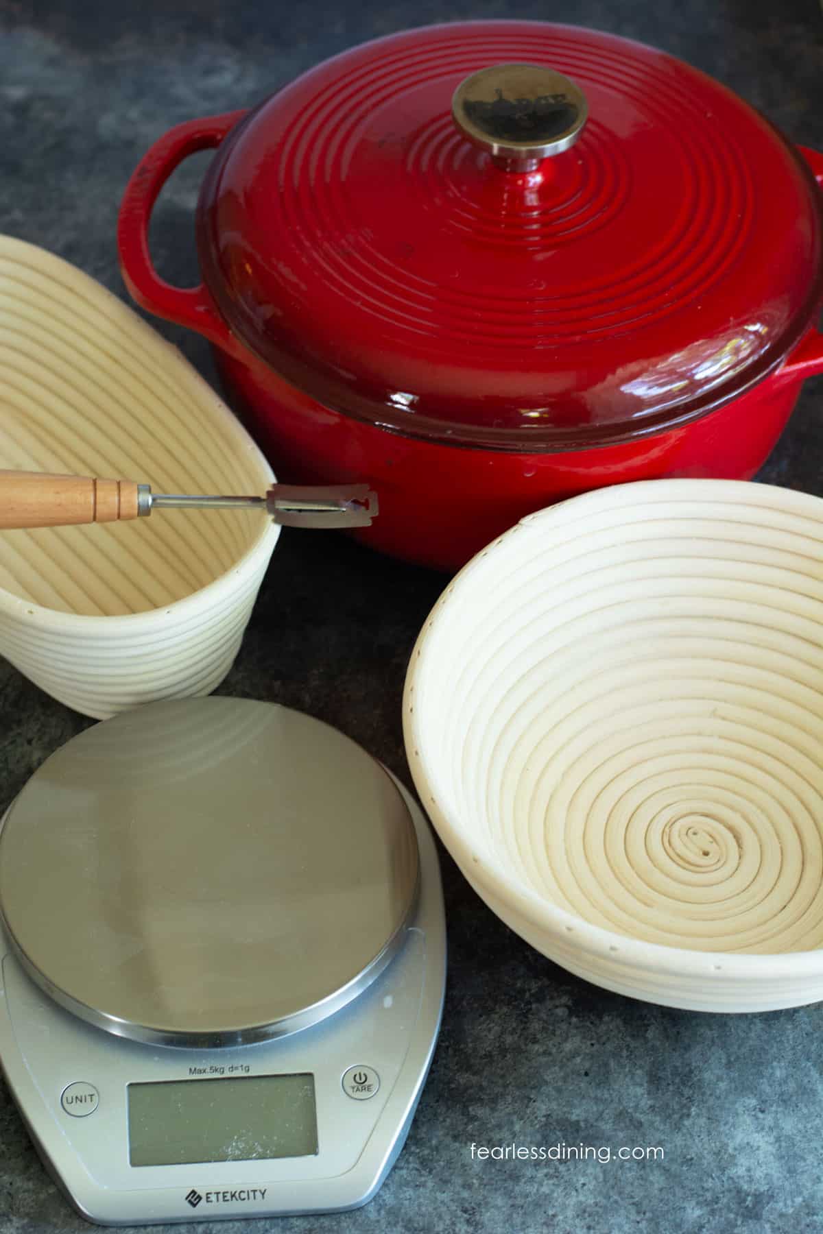 A photo of some of the sourdough tools I own. A digital scale, Dutch oven, bannetons, and a lame.