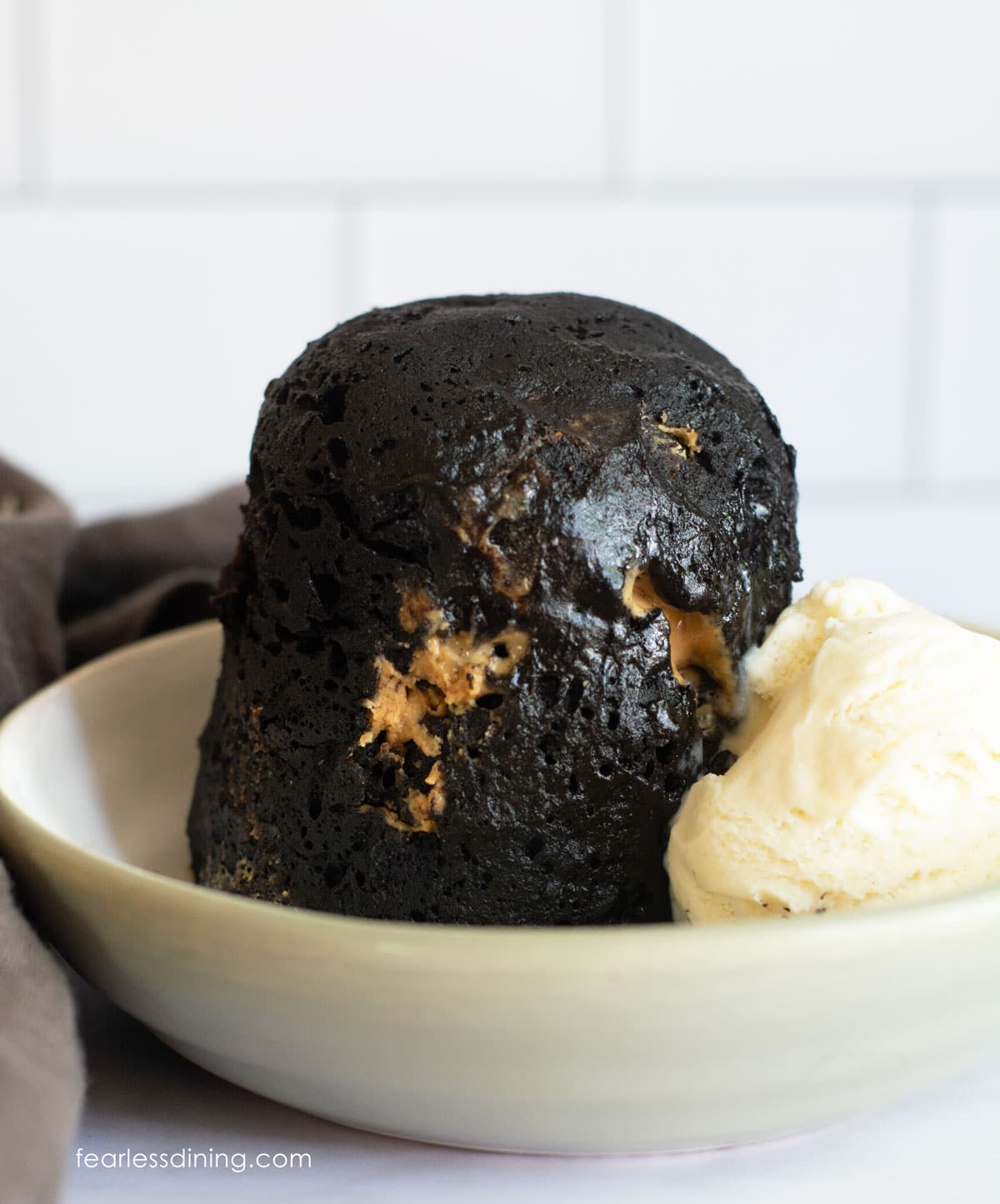 A chocolate peanut butter mug cake and vanilla ice cream in a small bowl.