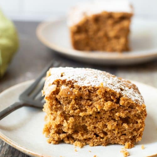 Two small plates, each with a slice of gluten free applesauce cake on them.