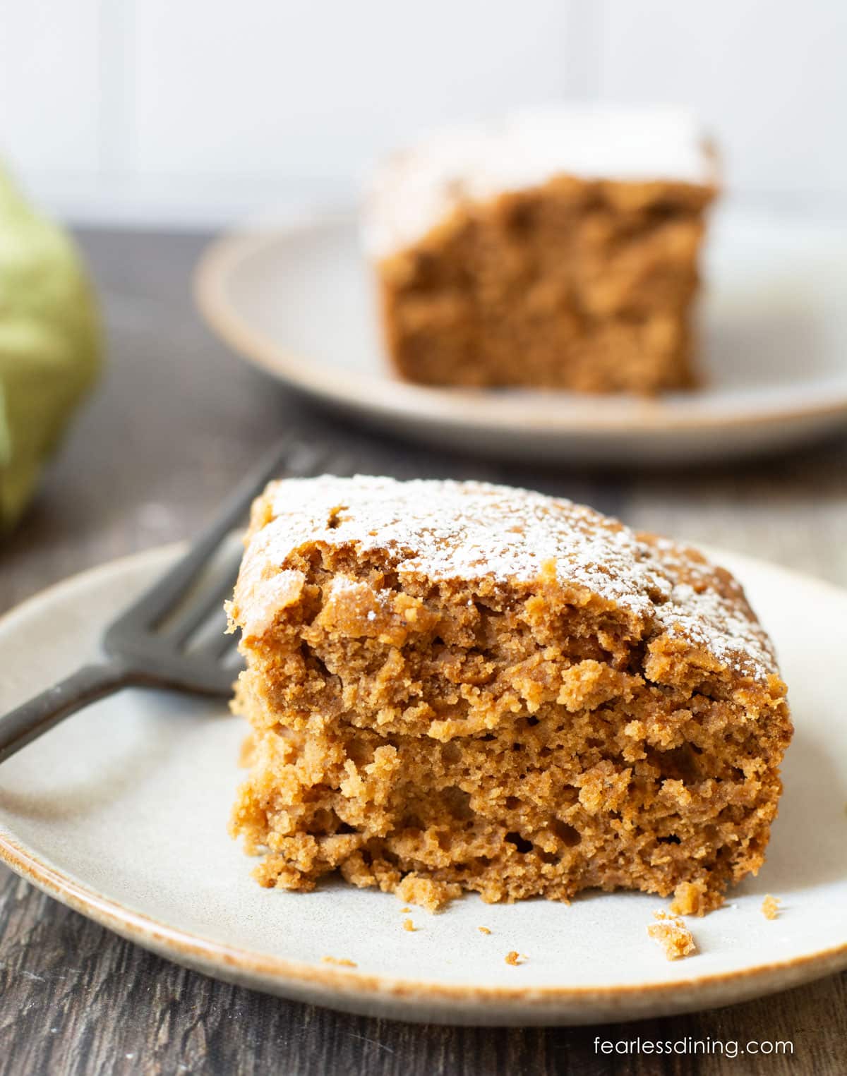 Two small plates, each with a slice of gluten free applesauce cake on them.