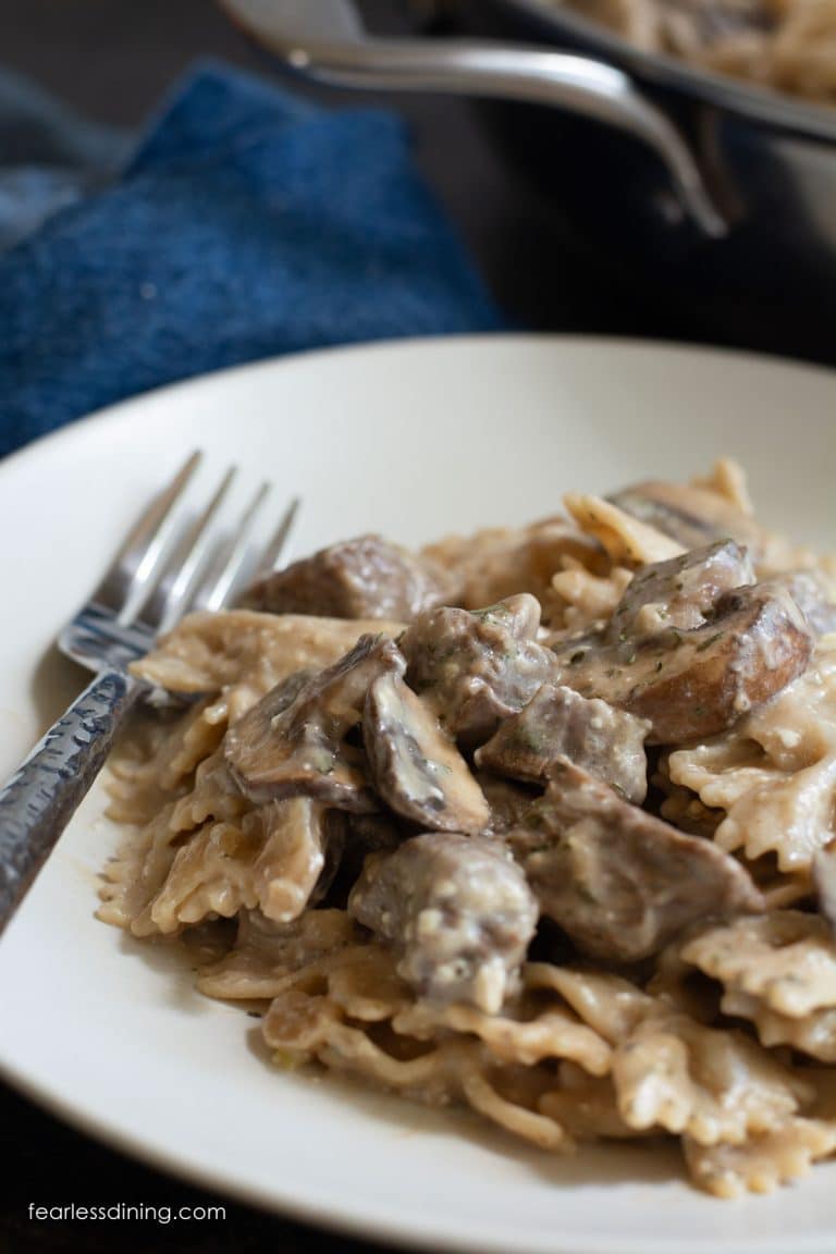 A closeup of a bowl of gluten free beef stroganoff next to the cooking pan.