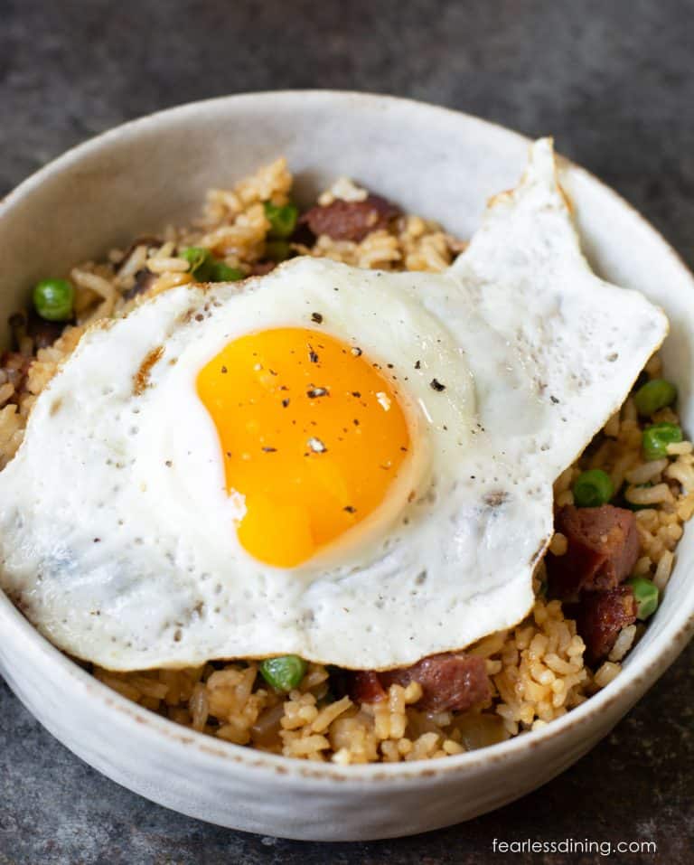 A bowl of breakfast fried rice with a sunny side up fried egg on top.