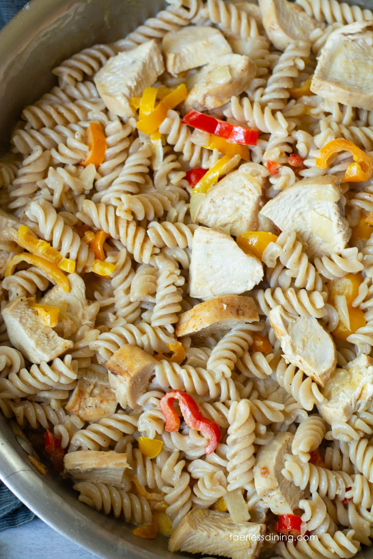A close up of the chicken and pasta in the pan.
