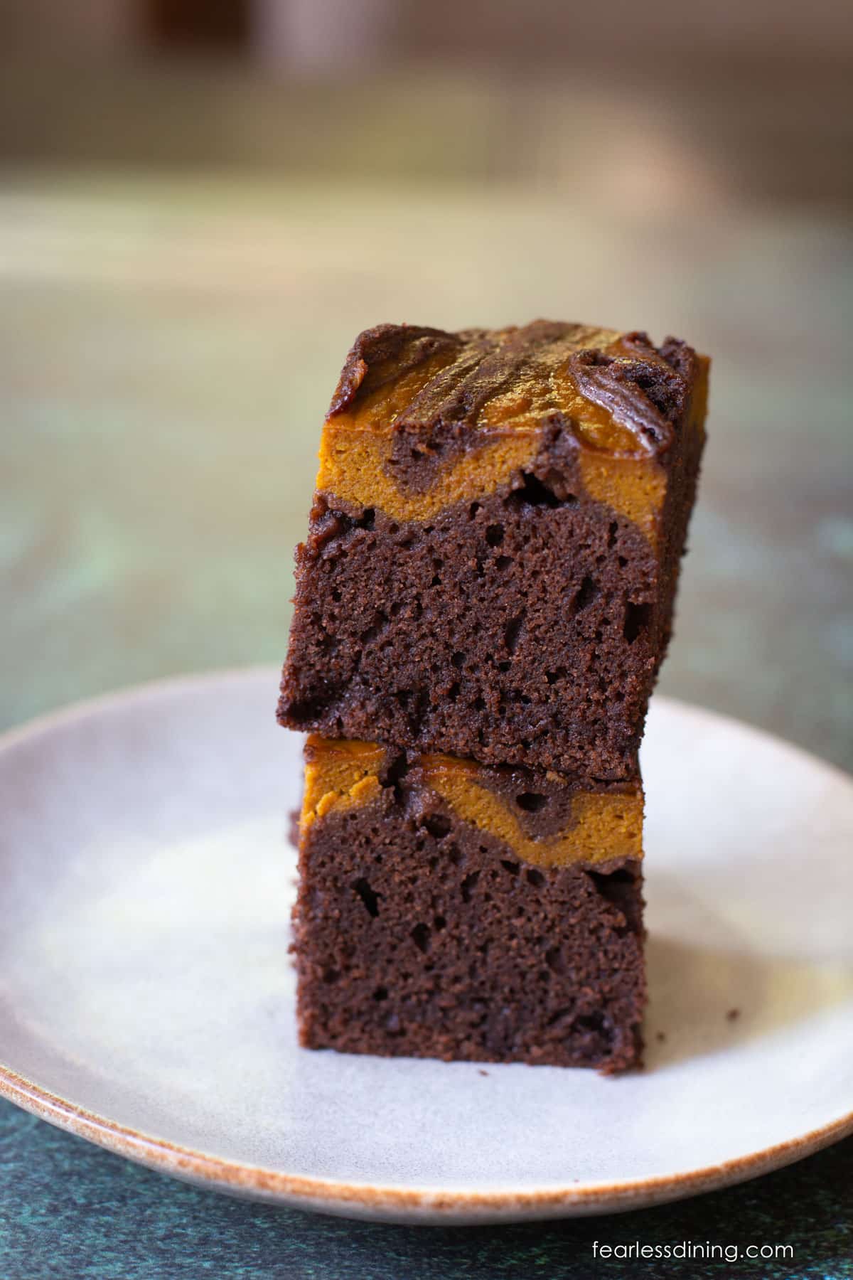 Two gluten free pumpkin swirled brownies stacked on top of each other.