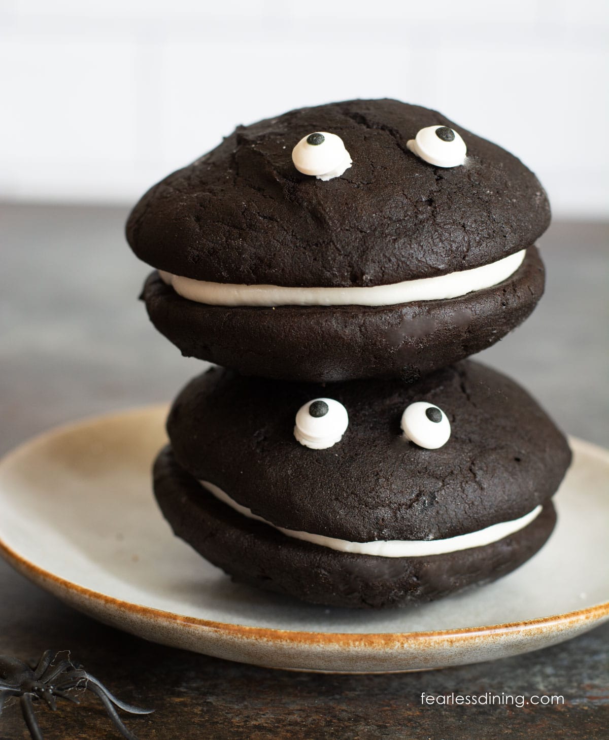 Two gluten free black velvet whoopie pies stacked on top of each other. They have googly eyes.