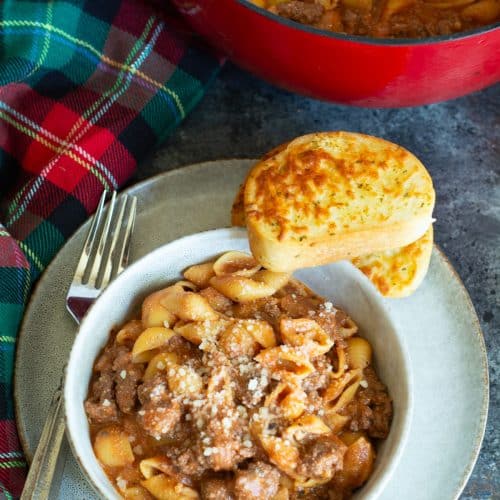 The top view of a bowl of gluten free creamy beef and shells. It has two slices of garlic toast on the bowl.