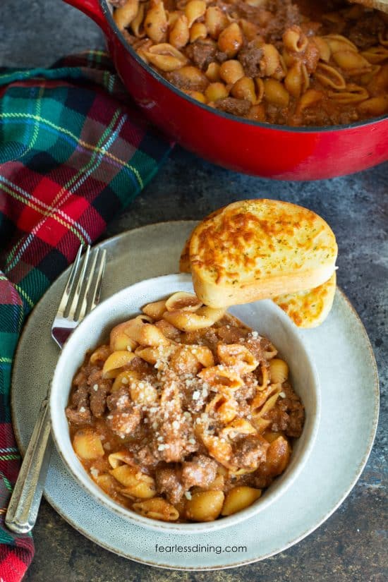 The top view of a bowl of gluten free creamy beef and shells. It has two slices of garlic toast on the bowl.