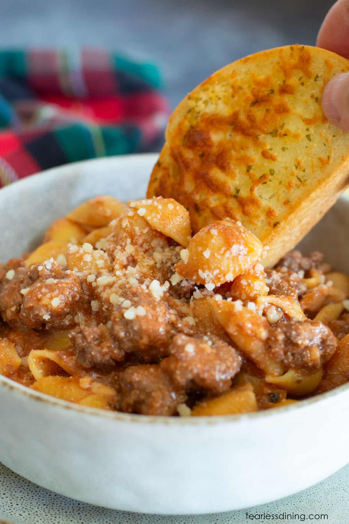 Dipping garlic toast into the saucy pasta.
