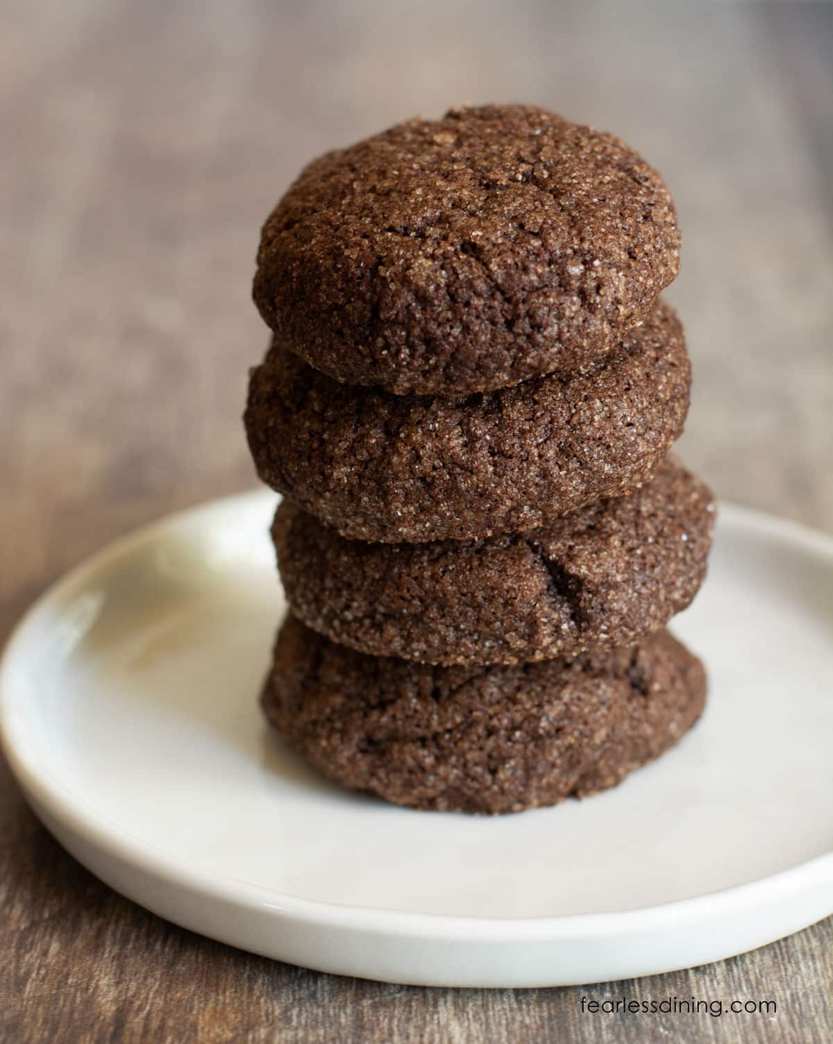 A stack of four gluten free chocolate snickerdoodle cookies on a white plate.