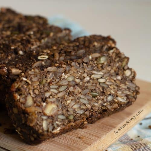 A photo of the sliced gluten free seed bread on a wooden cutting board.