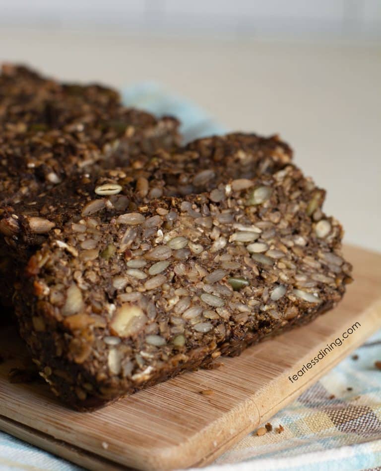 A photo of the sliced gluten free seed bread on a wooden cutting board.