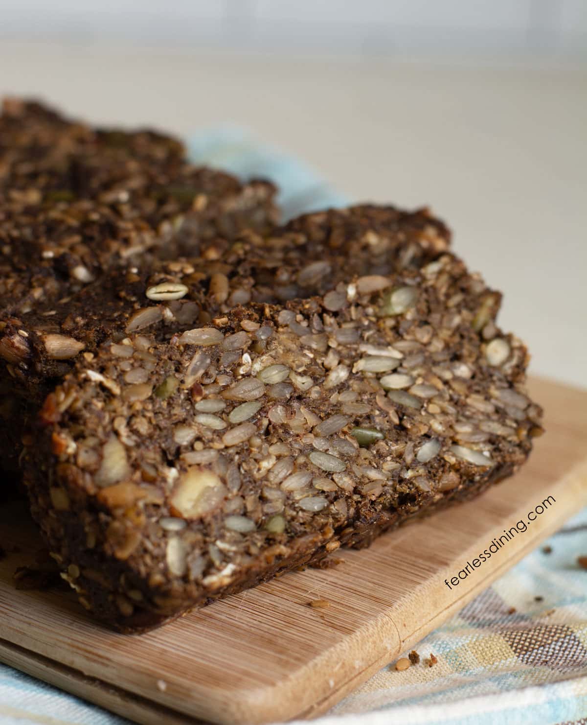 A photo of the sliced gluten free seed bread on a wooden cutting board.