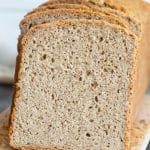 A loaf of gluten free buckwheat bread sliced on a cutting board.