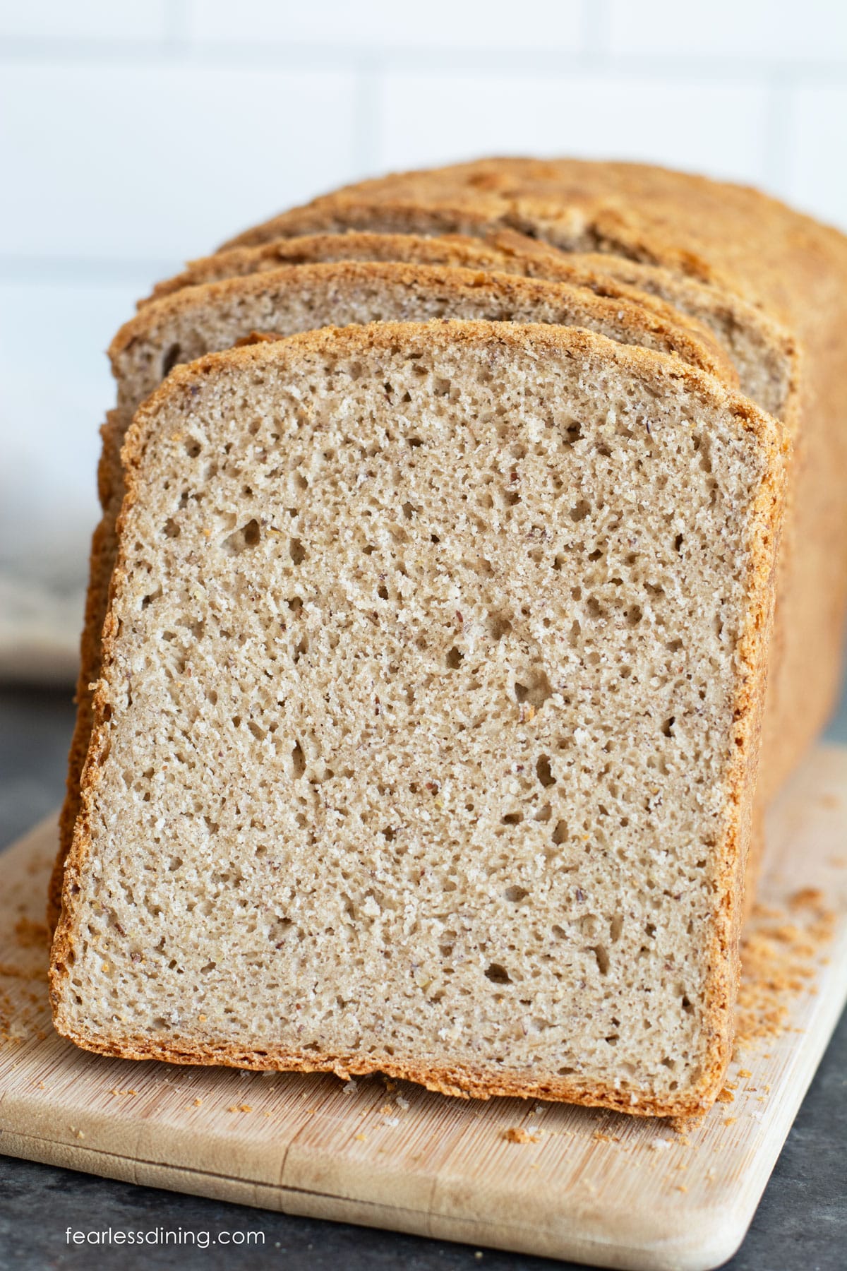A loaf of gluten free buckwheat bread sliced on a cutting board.