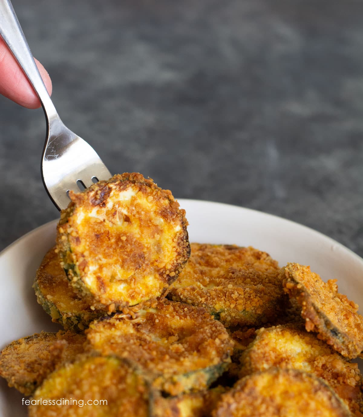 Picking up a fried zucchini chip from the bowl.