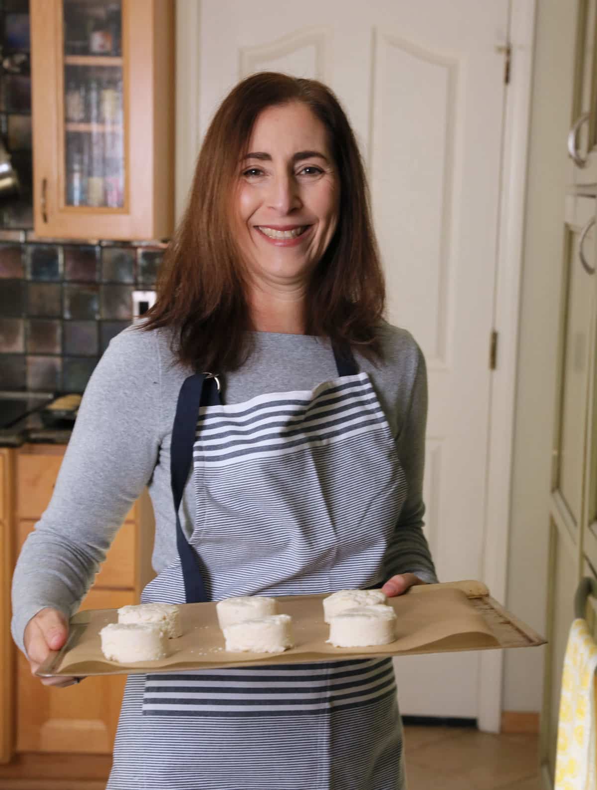 Sandi holding a tray of biscuits that are about to go in the oven to bake.