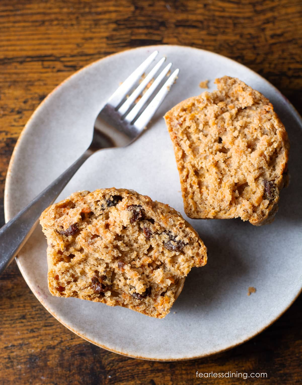 A carrot muffin cut in half on a small plate.