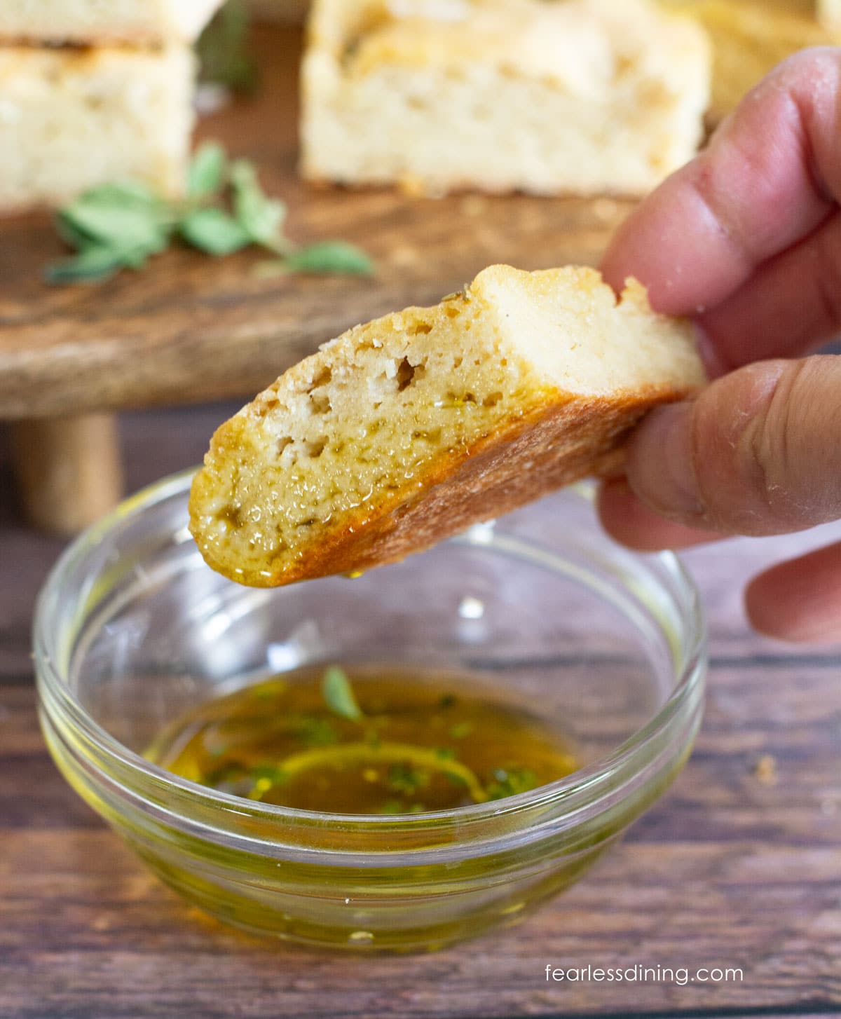 Dipping a piece of focaccia into herb infused oil.