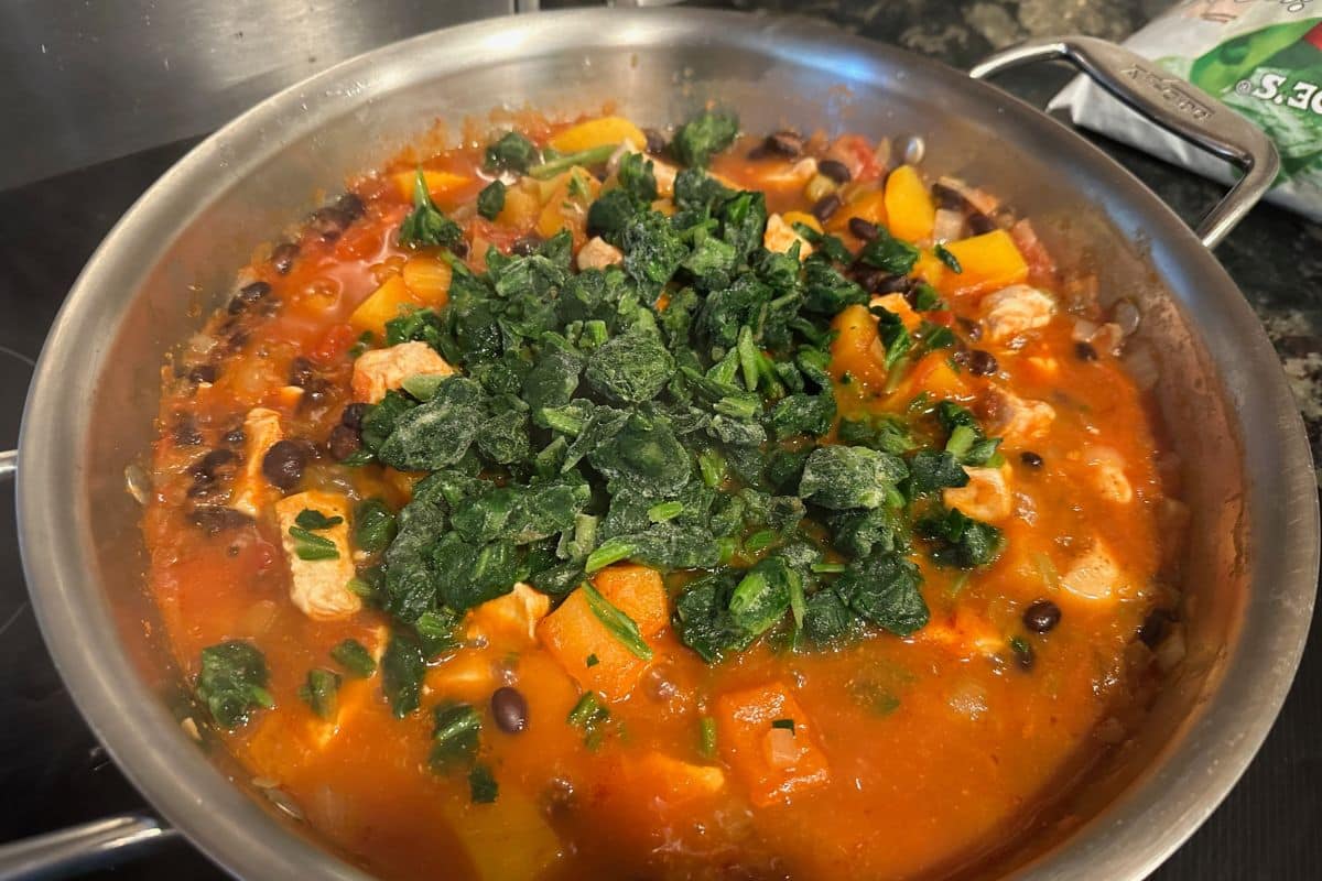 Adding the frozen spinach to the pan.