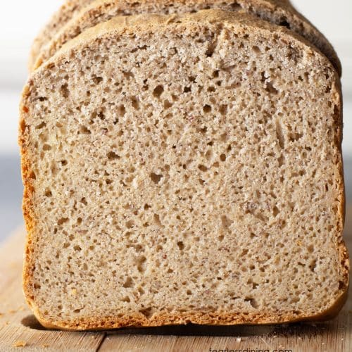 A loaf of gluten free bread sliced for sandwiches on a cutting board.