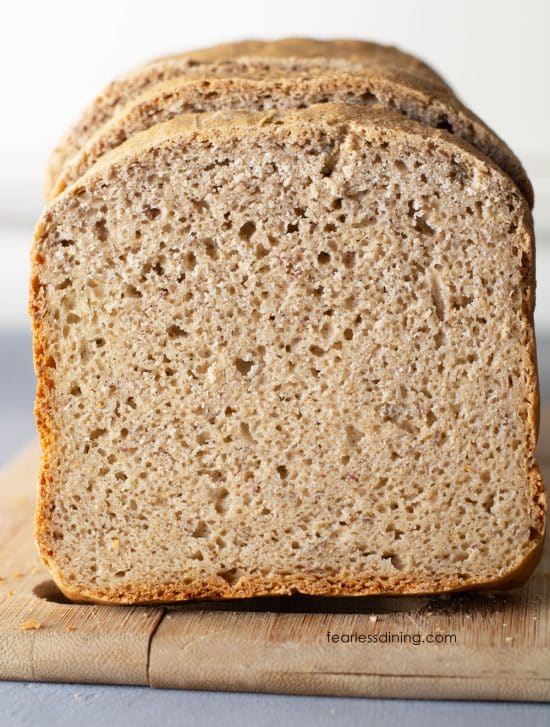 A loaf of gluten free bread sliced for sandwiches on a cutting board.