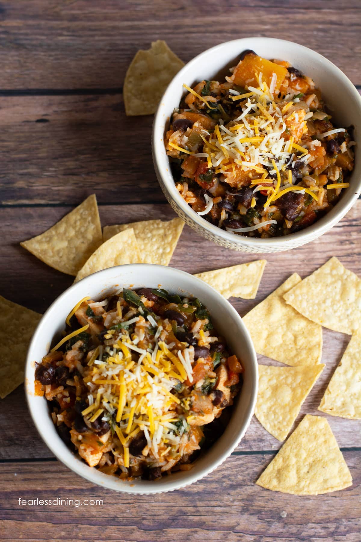 Two bowls of salsa chicken with tortilla chips.