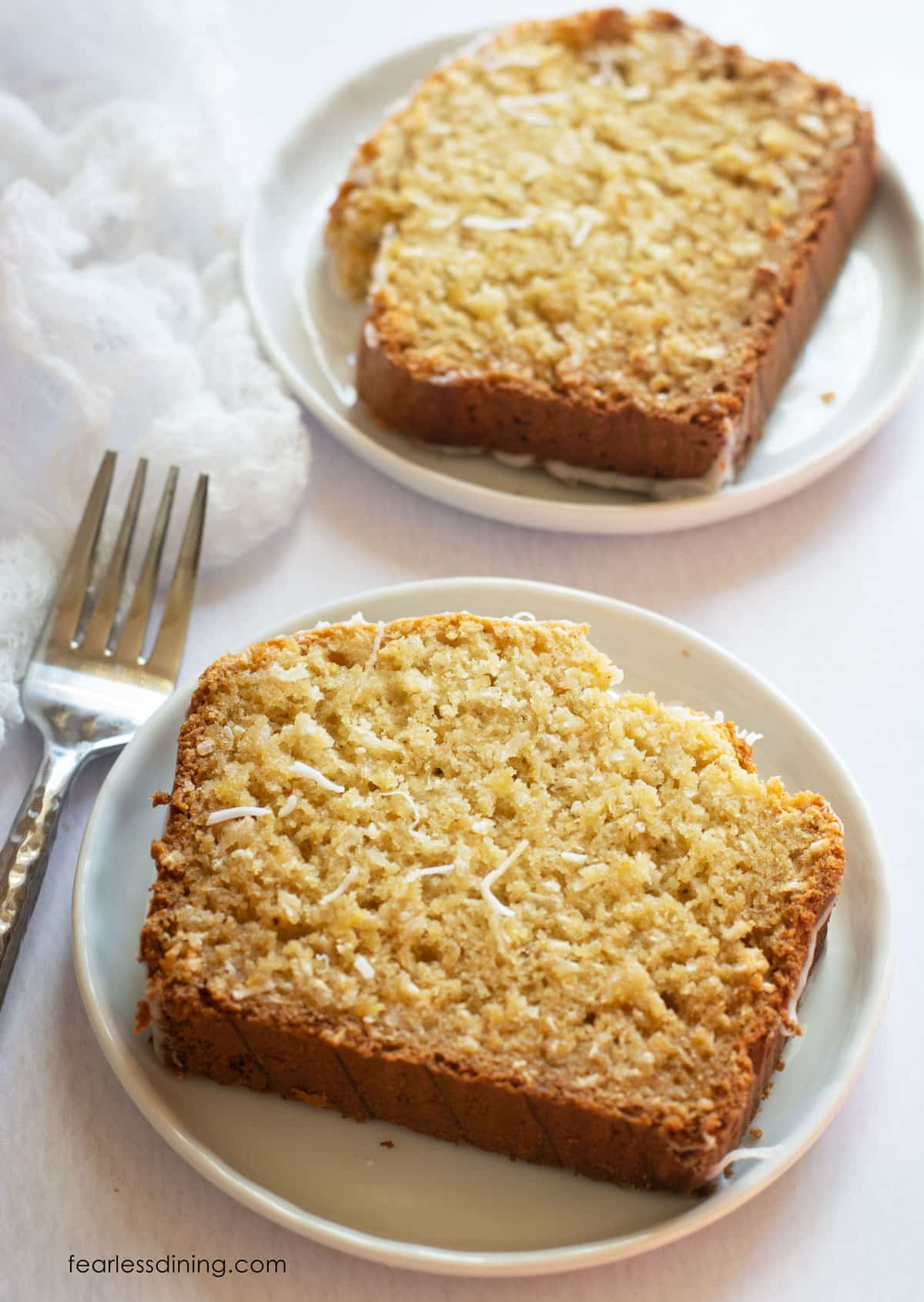 Two slices of the gluten-free coconut pineapple cake on small white plates.