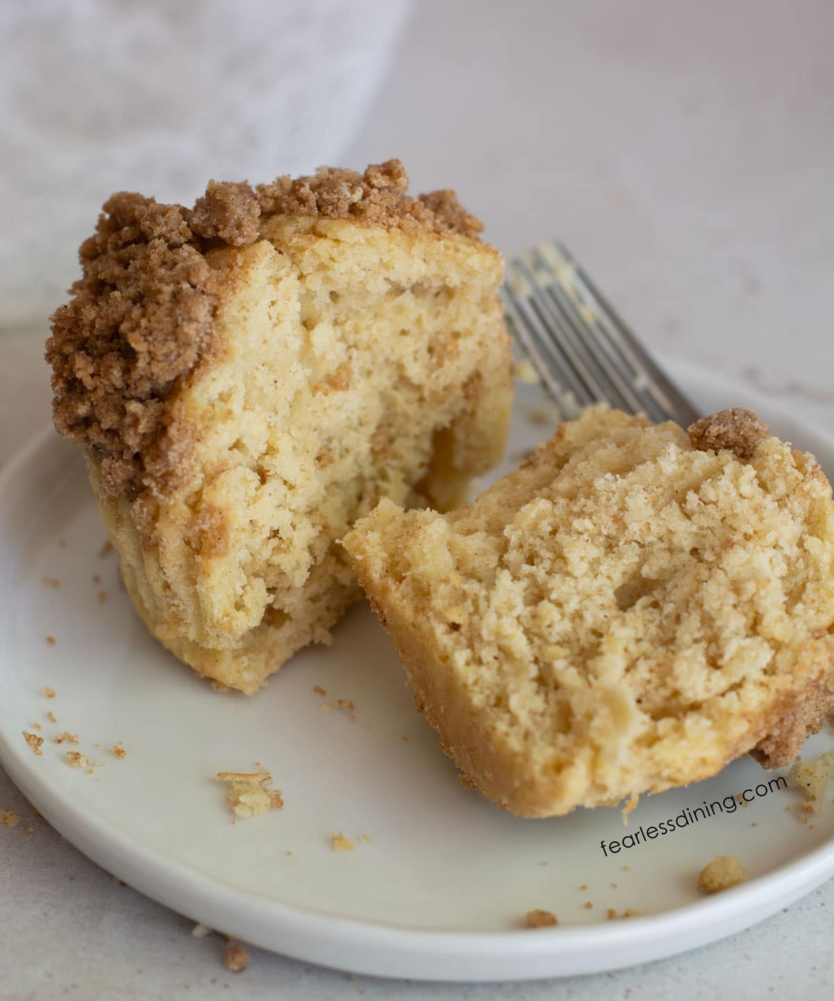 A gluten free coffee cake muffin cut in half so you can see the fluffy inside.