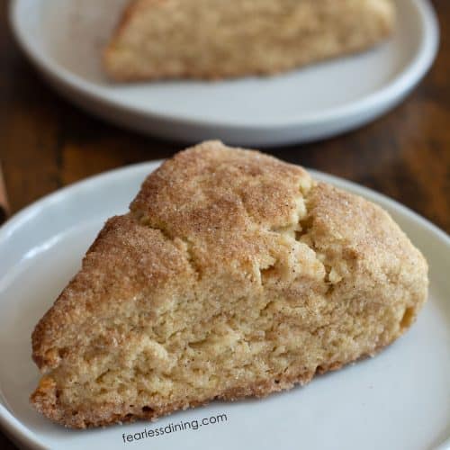 Two gluten free snickerdoodle scones on small white plates.
