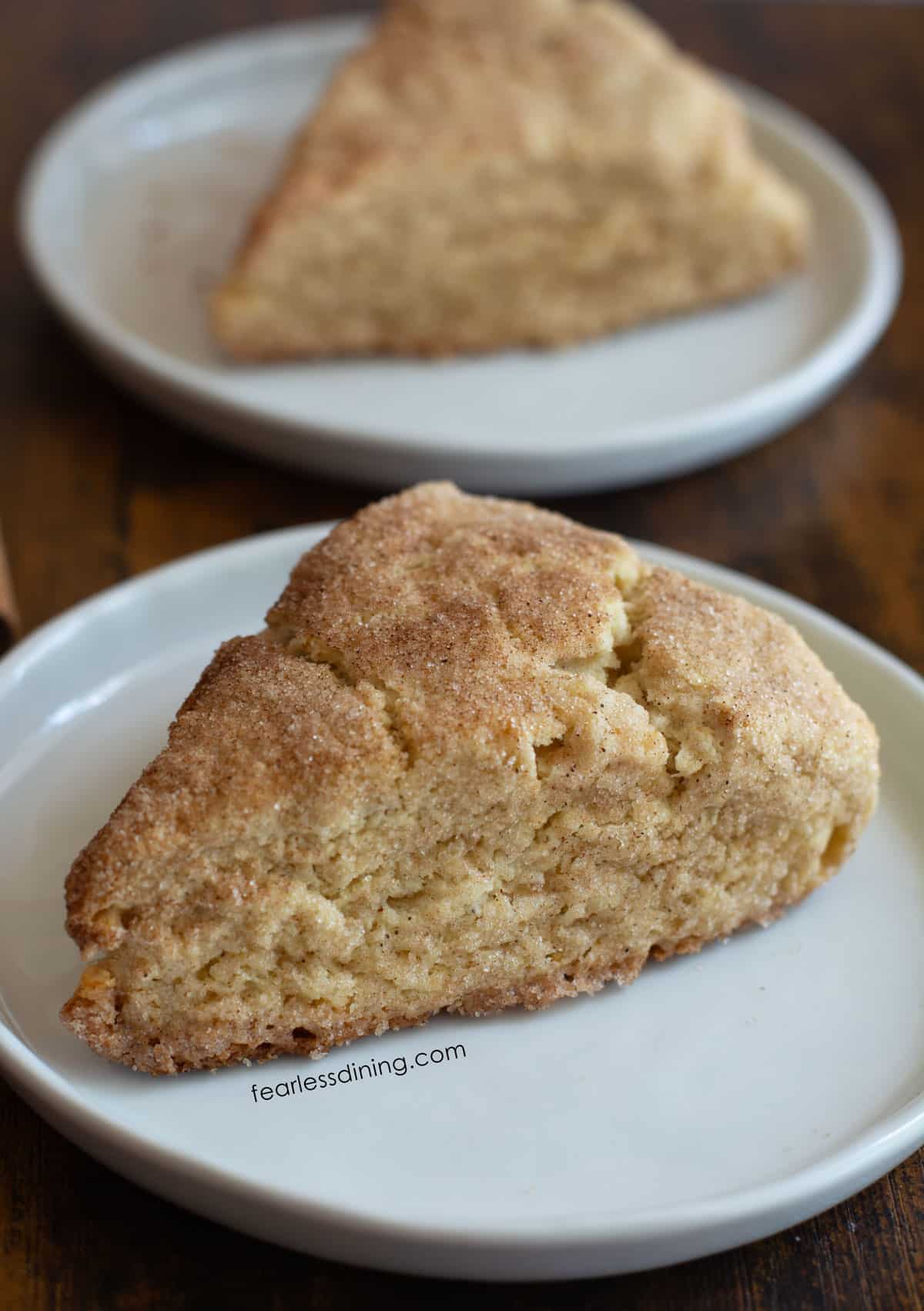 Two gluten free snickerdoodle scones on small white plates.