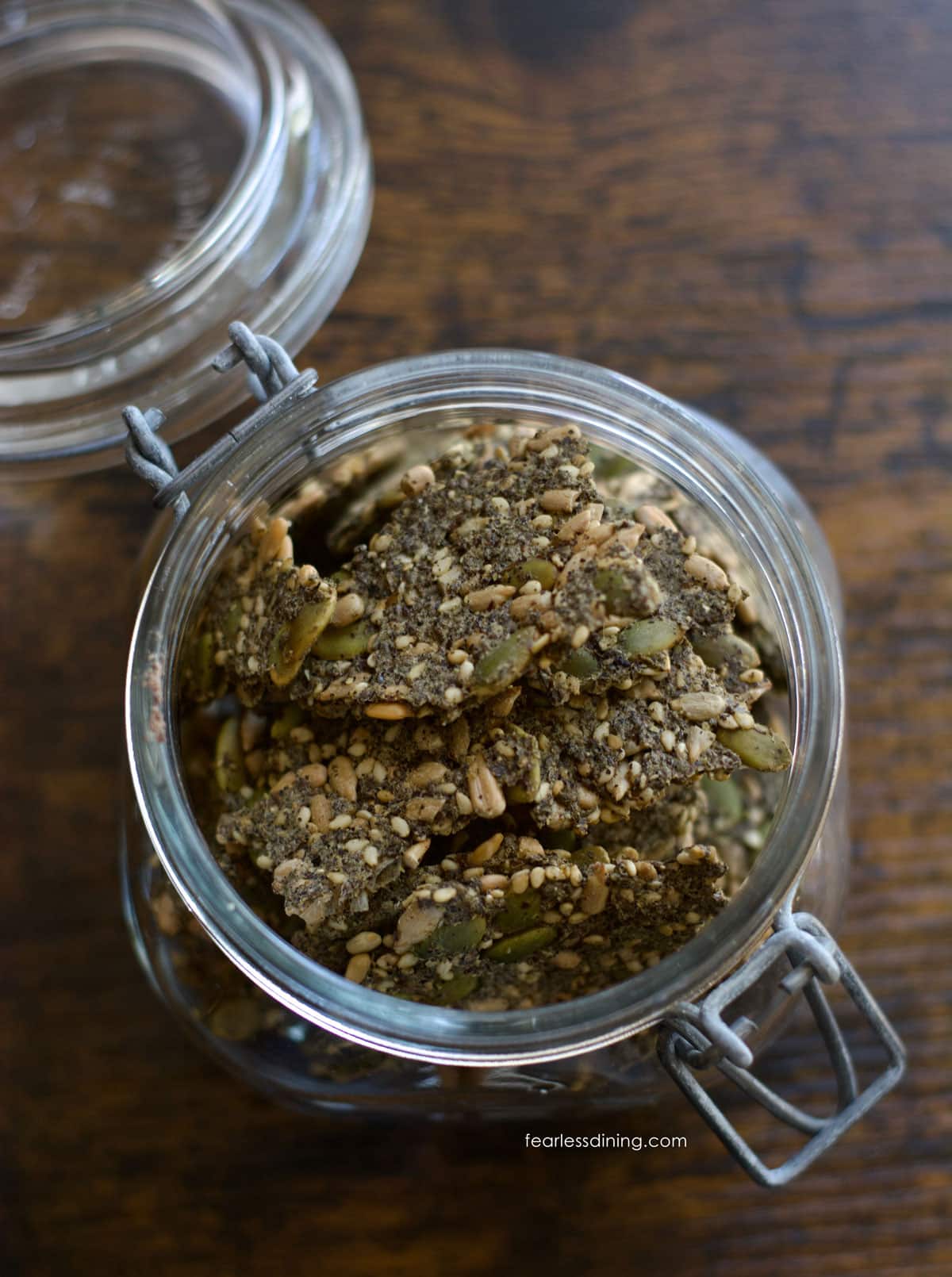 A mason jar filled with crispy gluten free seed crackers.